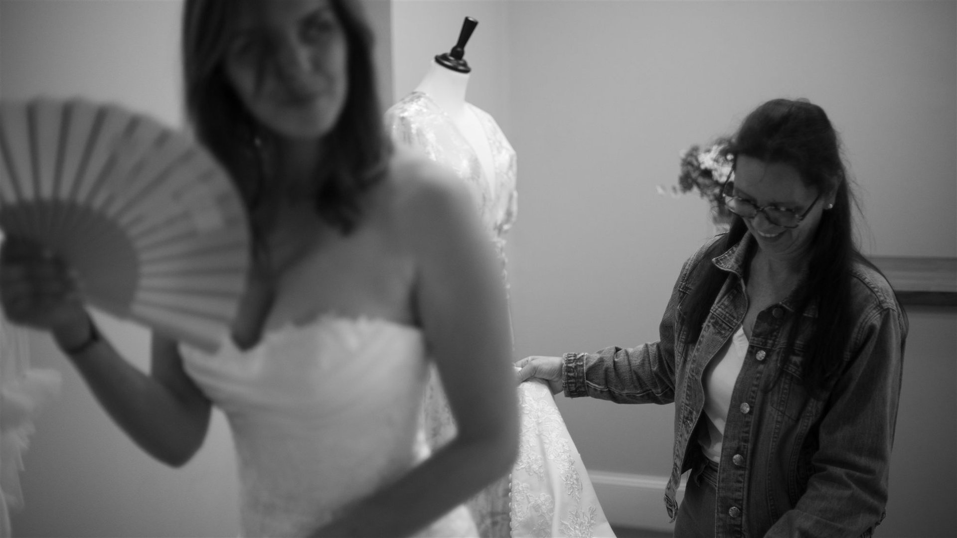 La mariée avec l'éventail en premier plan et son amie qui tient la traîne de la robe dentelle à Perpignan