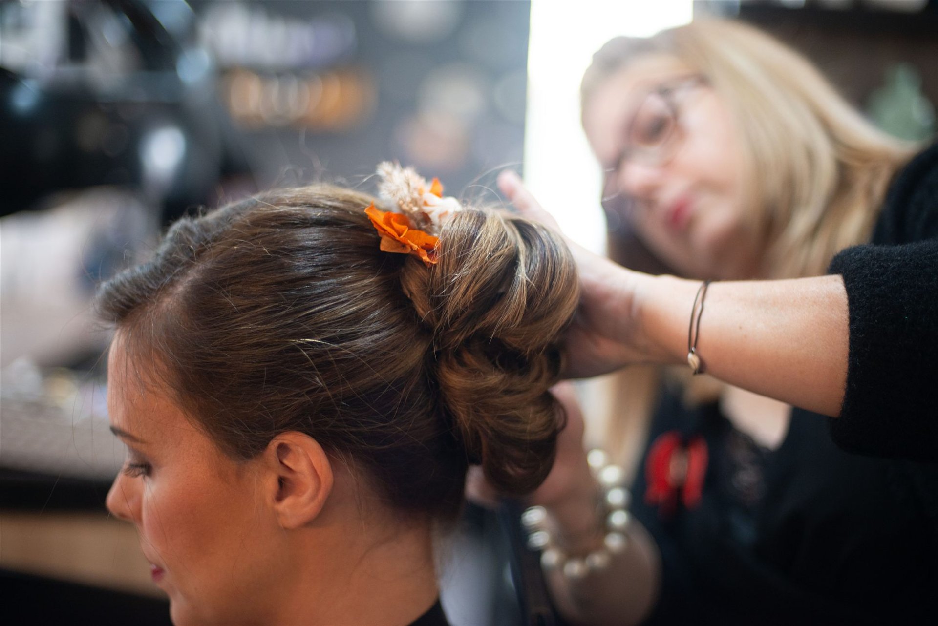 Première fleur orange de Mille Fleurs Sauvages posée dans le chignon d'Amandine par Annabel