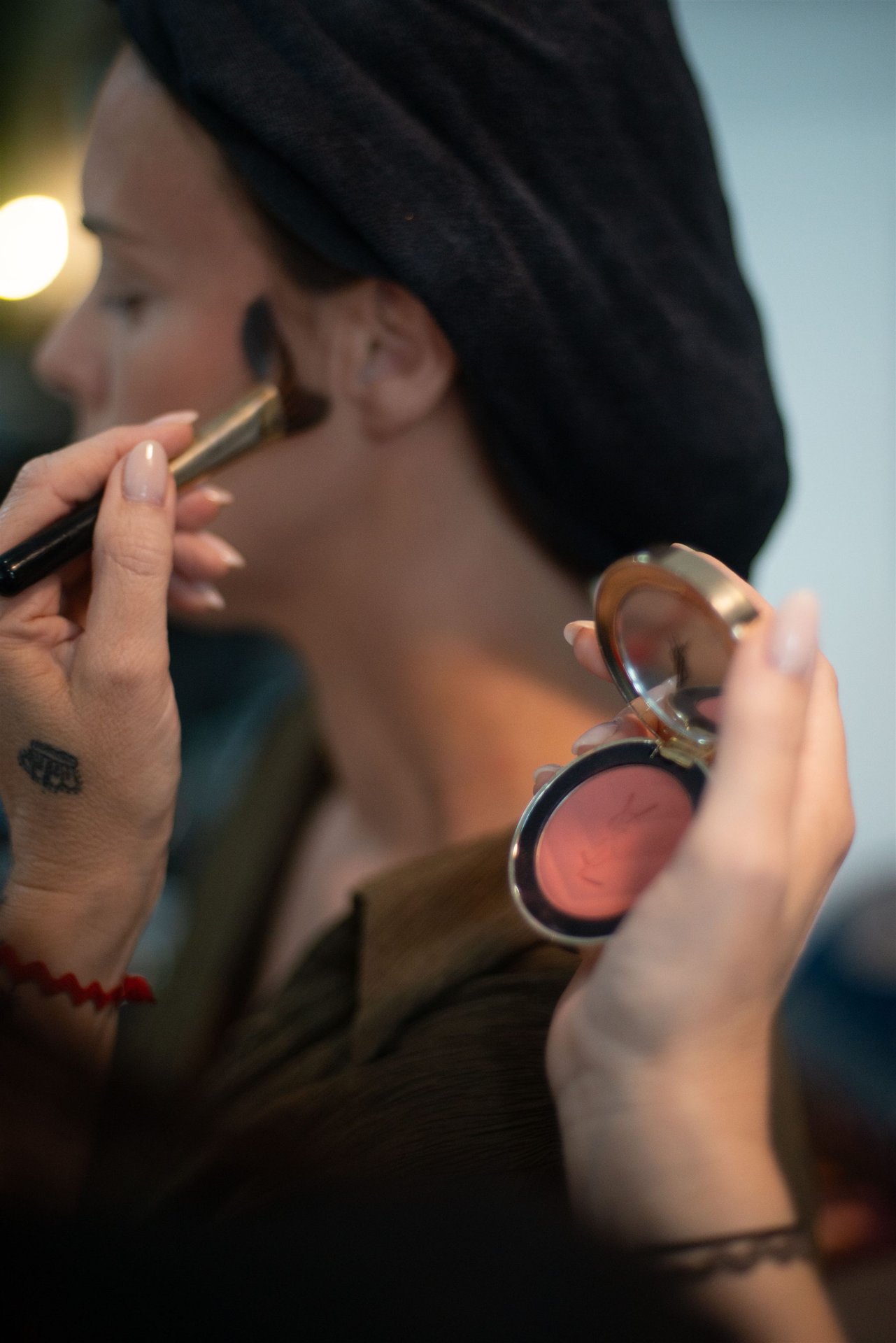 Application du blush sur les joues d'Amandine par Magali Esthétique — tête dans serviette noire, maquillage mariage