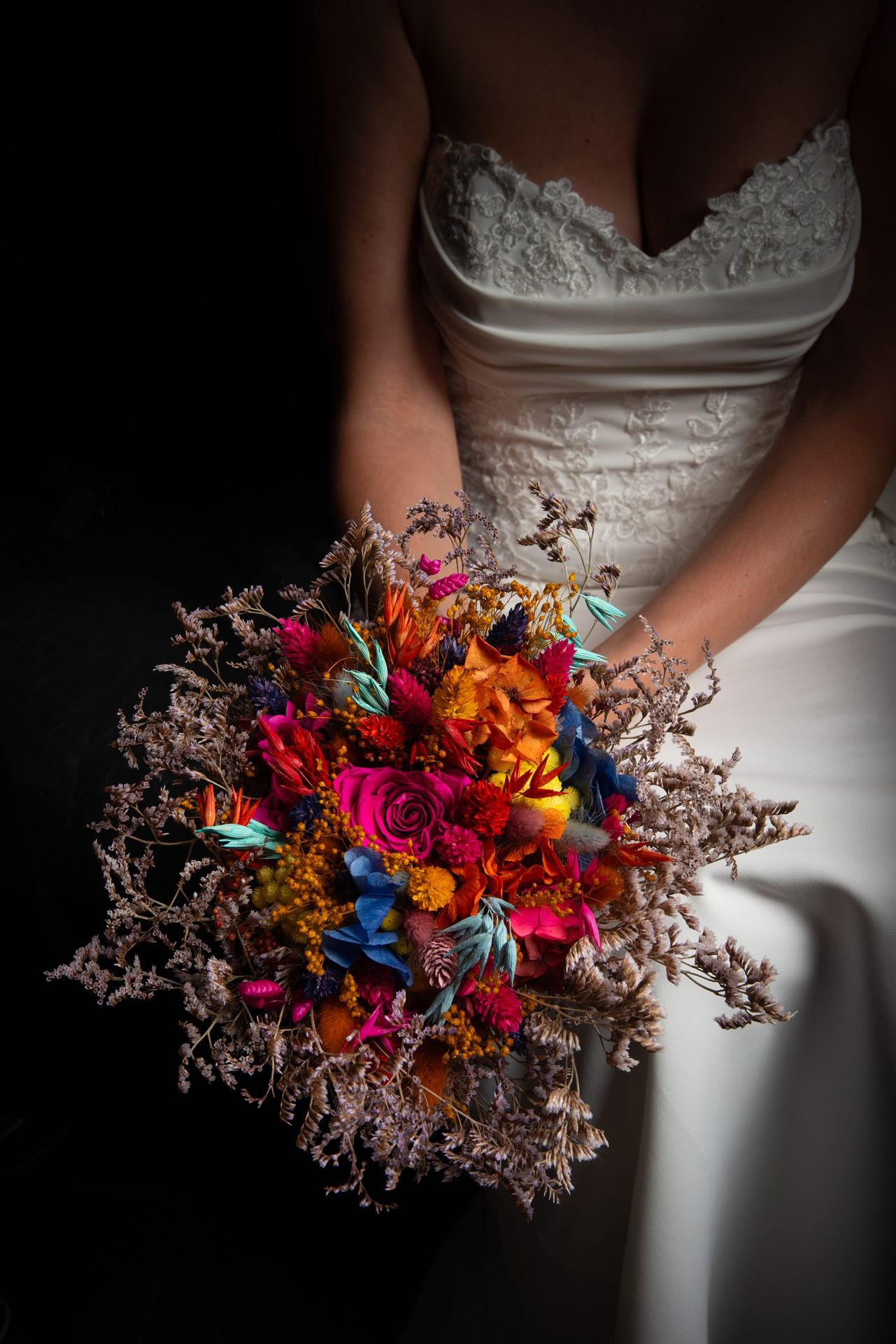Bouquet de mariée coloré — fuchsia, orange, bleu — tenu par la mariée en robe bustier dentelle — Mille Fleurs Sauvages Perpignan