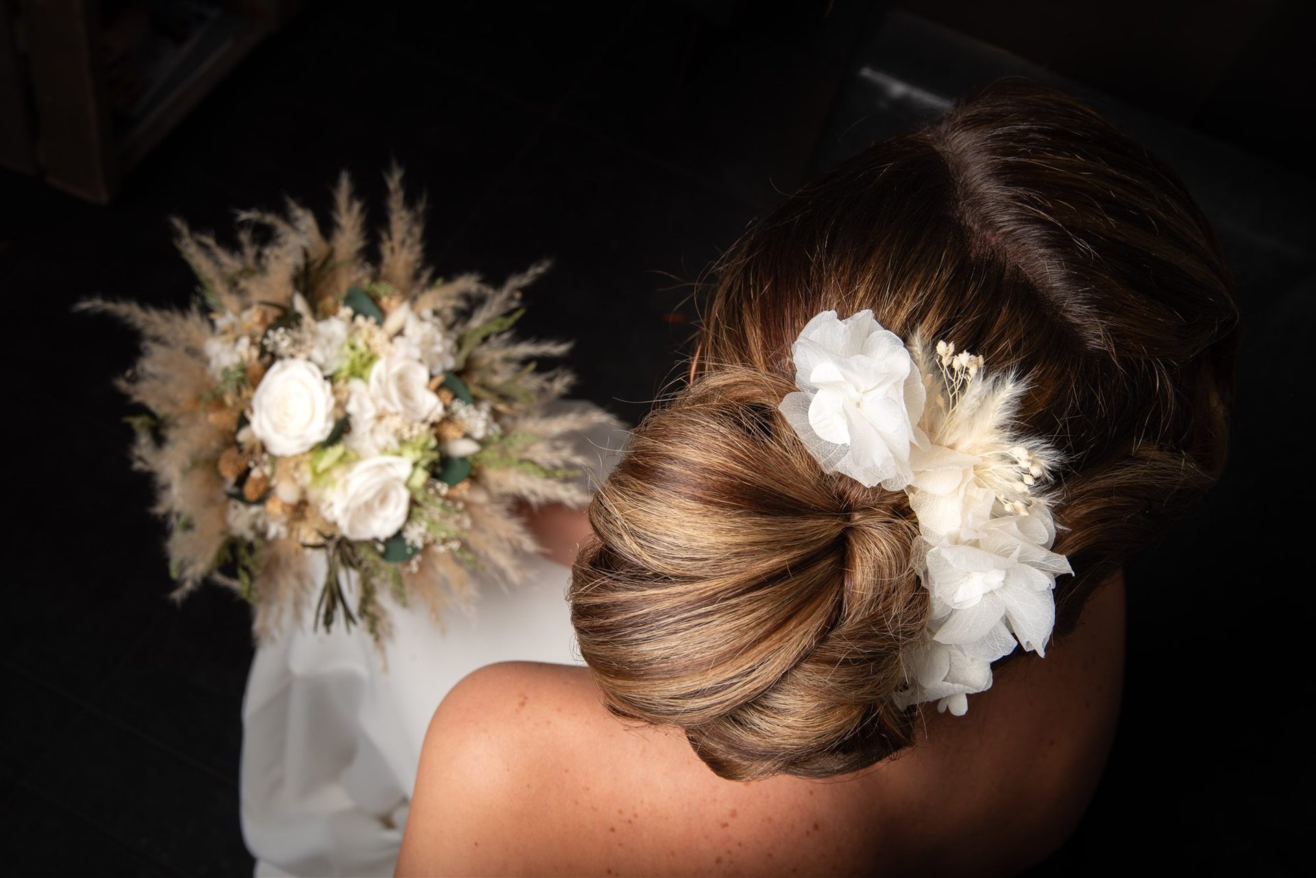 Vue de dos du chignon de mariée avec accessoire fleur blanche, bouquet pampas — coiffure de mariage Perpignan