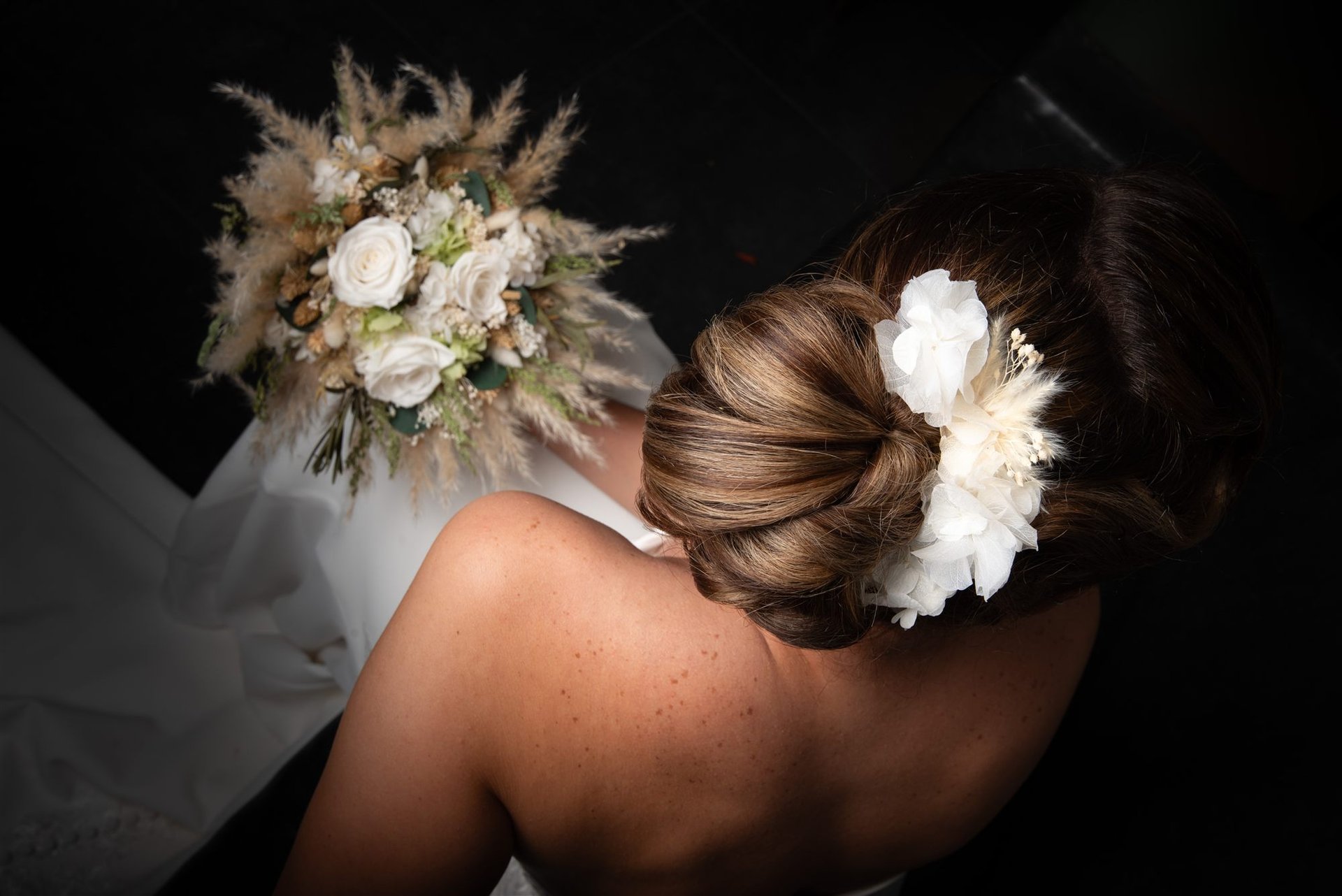 Dos de la mariée, chignon élaboré avec fleur blanche, bouquet de pampas — coiffure mariage Salon D'Ana Perpignan